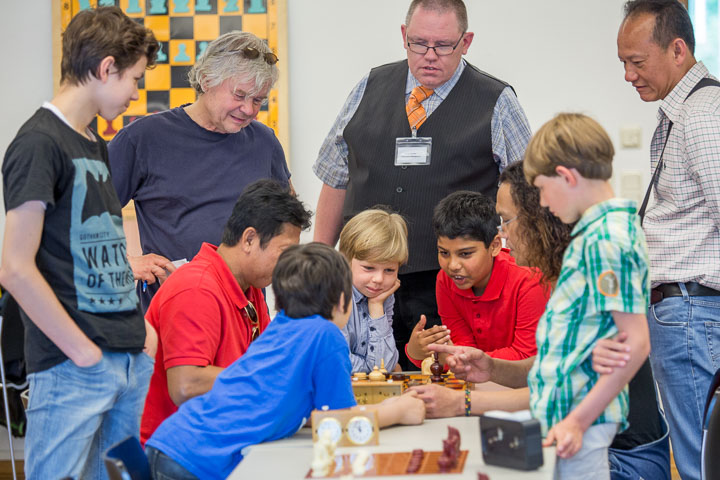 Der Meister und seine Schüler. Turniersieger Weeraphon Junrasatpanich (stehend ganz rechts) beobachtet das Treffen zwischen Surasak Pradaenschat (halb verdeckt im roten T-Shirt links am Brett) und Sumet 'Thon' Kraiphlaeng (halb verdeckt rechts am Brett) in der letzten Runde. Und die Turnierleitung ist natürlich auch vor Ort: René Gralla (stehend hinten links) und Jürgen Woscidlo. Foto: Christoph Harder